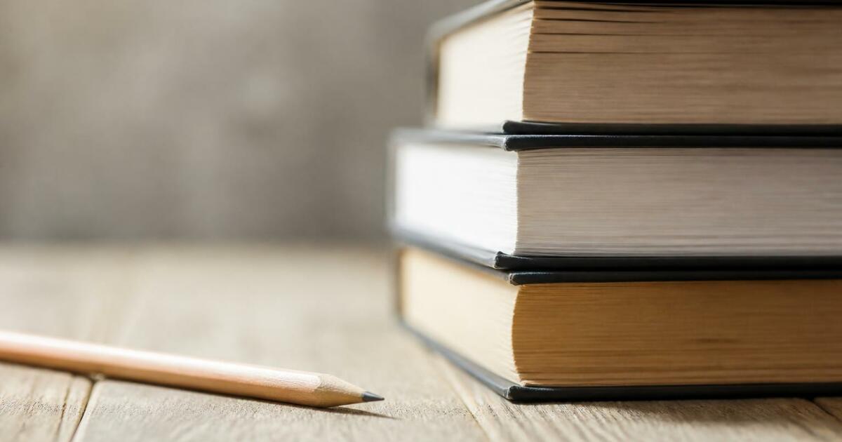 Стопка книг и карандаш на деревянной поверхност...
